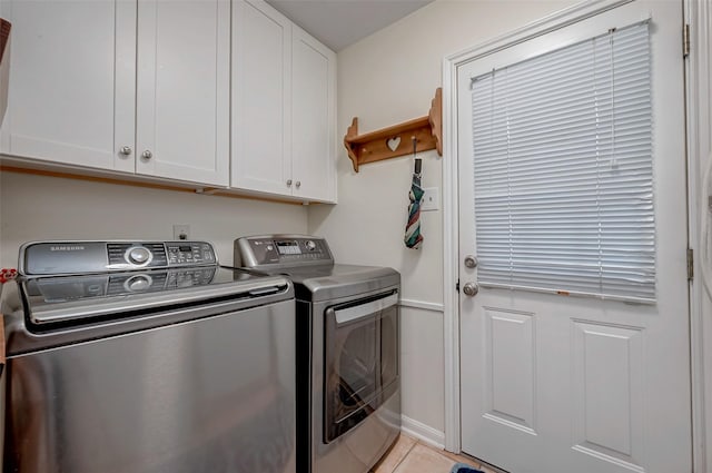 clothes washing area featuring washing machine and dryer, cabinet space, baseboards, and light tile patterned flooring