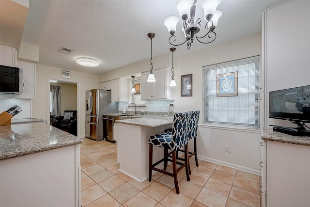 kitchen with light tile patterned floors, white cabinets, dishwasher, a peninsula, and backsplash