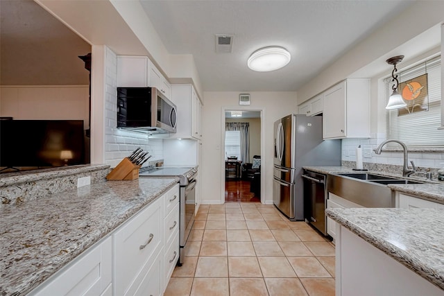 kitchen featuring light tile patterned floors, visible vents, appliances with stainless steel finishes, light stone counters, and a sink