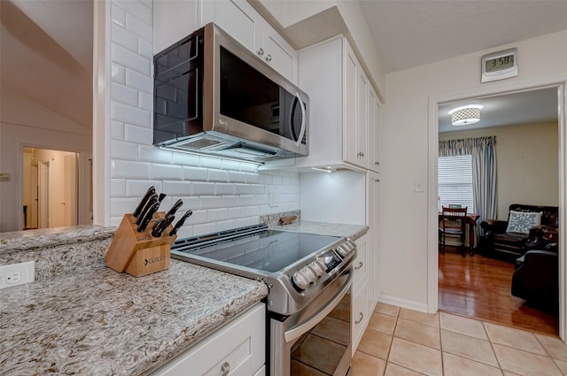 kitchen featuring light stone countertops, appliances with stainless steel finishes, white cabinets, and light tile patterned flooring