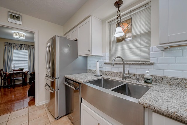 kitchen featuring white cabinetry, dishwasher, a sink, and light tile patterned floors