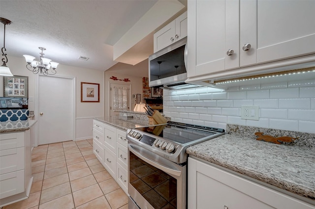 kitchen featuring a textured ceiling, light tile patterned flooring, stainless steel appliances, white cabinets, and tasteful backsplash