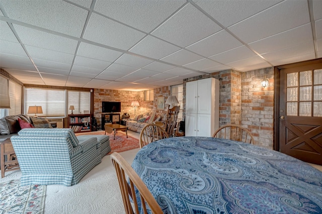 bedroom featuring a drop ceiling and brick wall