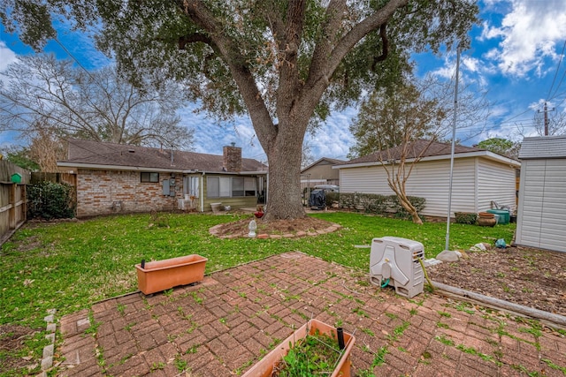 rear view of property featuring an outbuilding, a fenced backyard, brick siding, a lawn, and a patio area