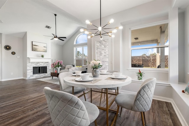 dining space featuring lofted ceiling, visible vents, a stone fireplace, and wood finished floors