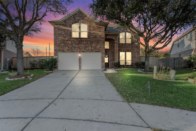 traditional-style home with brick siding, a yard, concrete driveway, an attached garage, and fence