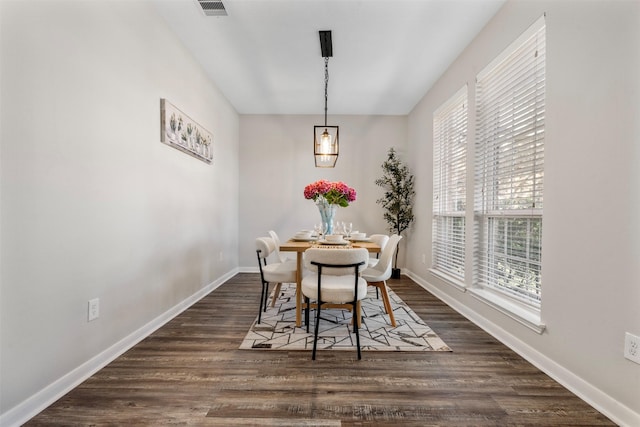 dining space with dark wood-style flooring, visible vents, and baseboards