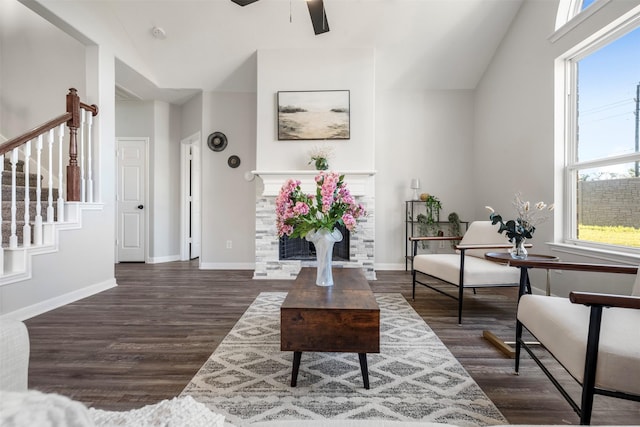 living area with a fireplace, stairway, baseboards, and wood finished floors