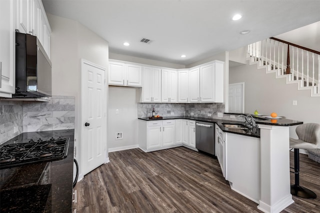 kitchen featuring dark wood-style flooring, stainless steel appliances, visible vents, a sink, and a peninsula