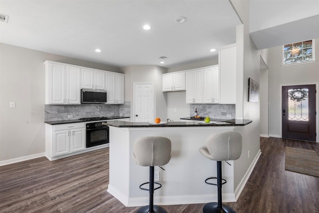 kitchen with dark countertops, white cabinetry, a peninsula, and black appliances