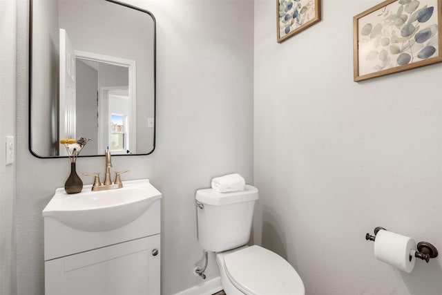 bathroom with toilet, baseboards, and vanity