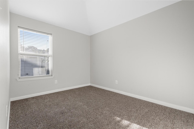 spare room featuring carpet floors, baseboards, and vaulted ceiling