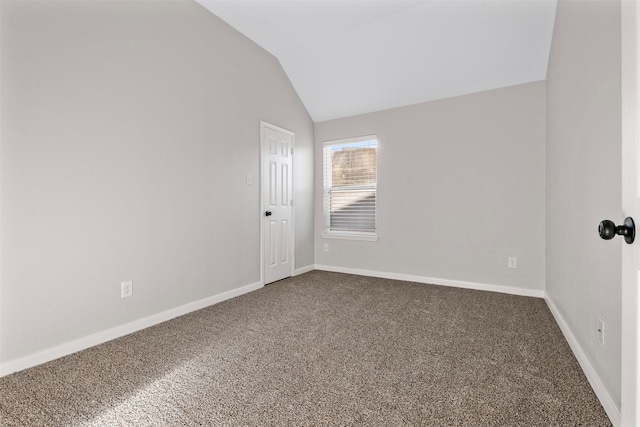 carpeted empty room featuring lofted ceiling and baseboards