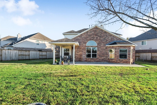 rear view of property with brick siding, a lawn, a patio area, and a fenced backyard