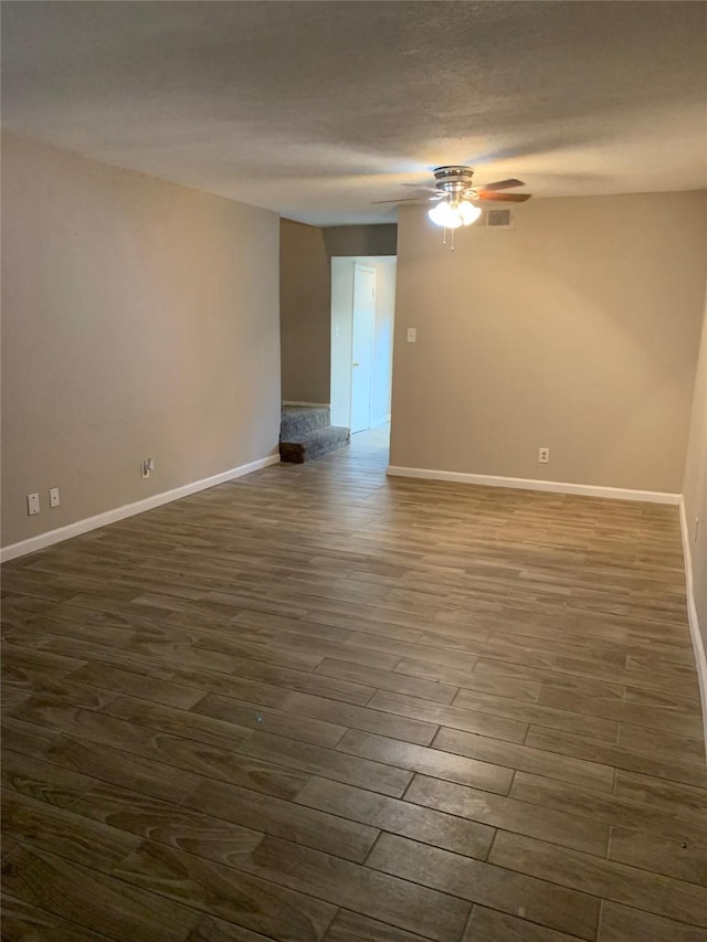 unfurnished room featuring dark wood finished floors, visible vents, a ceiling fan, a textured ceiling, and baseboards