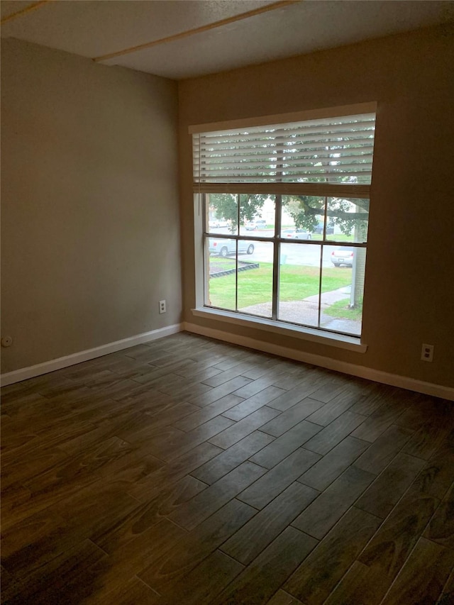 empty room with dark wood-style floors and baseboards