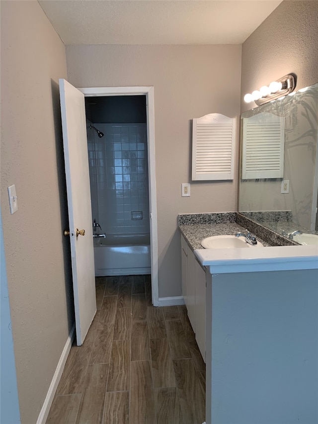 bathroom featuring wood tiled floor, washtub / shower combination, baseboards, and vanity