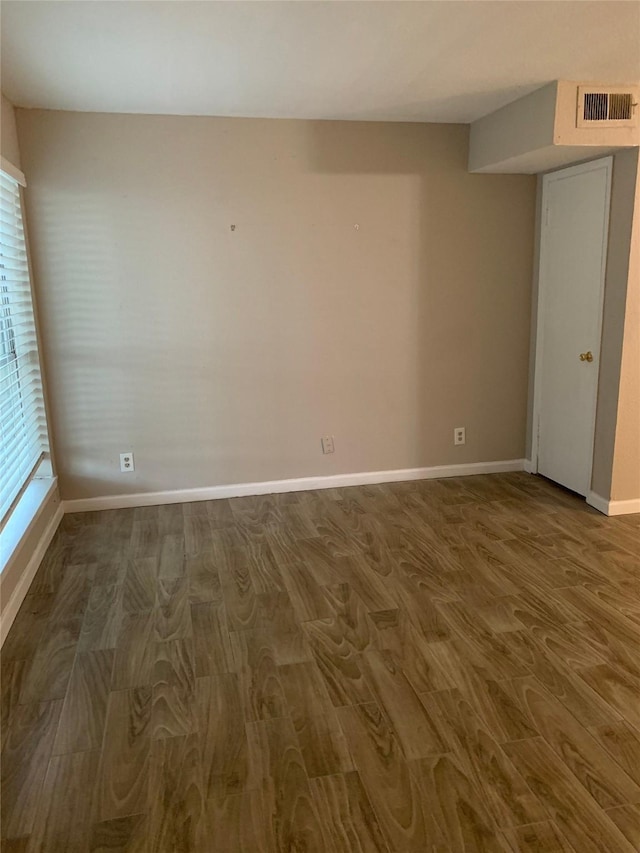 unfurnished room featuring visible vents, baseboards, and wood finished floors