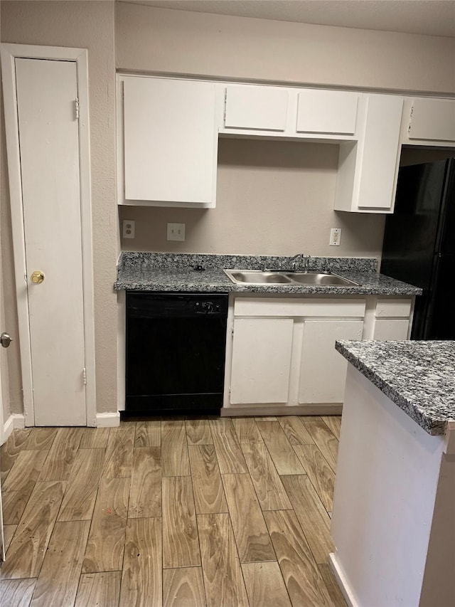 kitchen with dark countertops, wood tiled floor, white cabinets, a sink, and black appliances