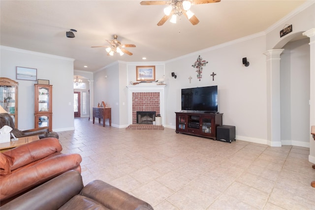 living room with ceiling fan, a fireplace, baseboards, ornamental molding, and ornate columns