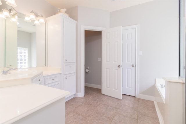 bathroom with tile patterned flooring, vanity, baseboards, and a bath