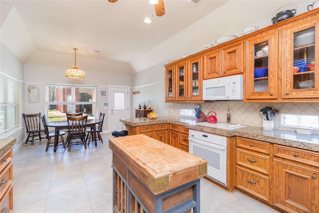 kitchen with white appliances, tasteful backsplash, vaulted ceiling, and brown cabinetry