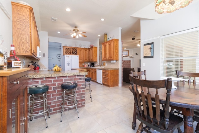 kitchen featuring a peninsula, white appliances, visible vents, and a ceiling fan