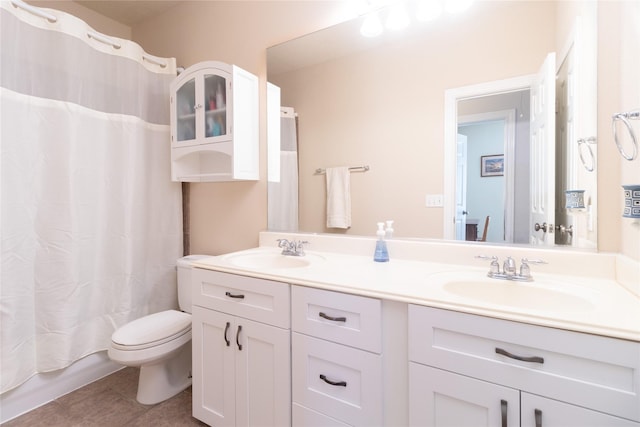 bathroom with tile patterned floors, a sink, toilet, and double vanity