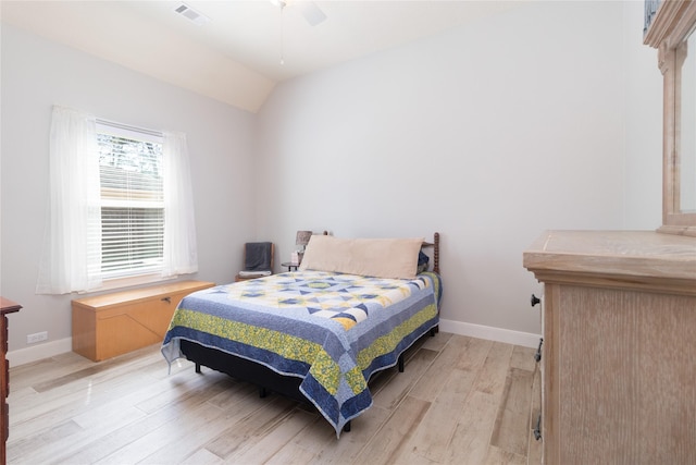 bedroom featuring light wood-style flooring, visible vents, vaulted ceiling, and baseboards