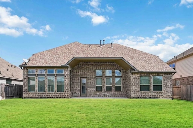 back of property featuring brick siding, a lawn, and a fenced backyard