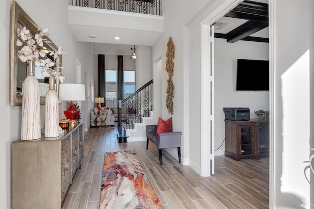 entryway featuring baseboards, a high ceiling, stairway, and wood finish floors