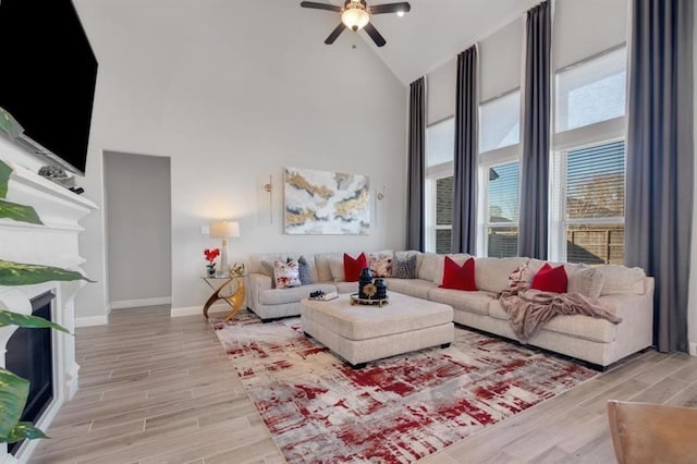 living area featuring a fireplace, high vaulted ceiling, and wood finish floors