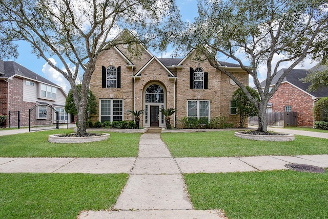 traditional-style home featuring brick siding, fence, and a front lawn