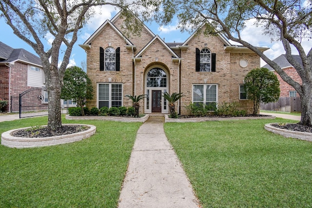 traditional home featuring fence, a front lawn, and brick siding