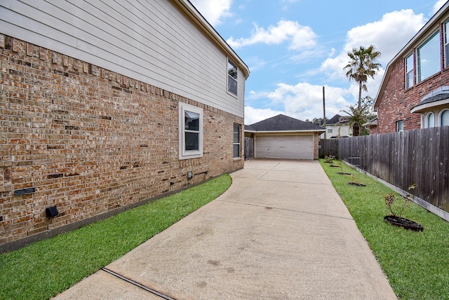 view of property exterior featuring a detached garage, fence, a lawn, and brick siding