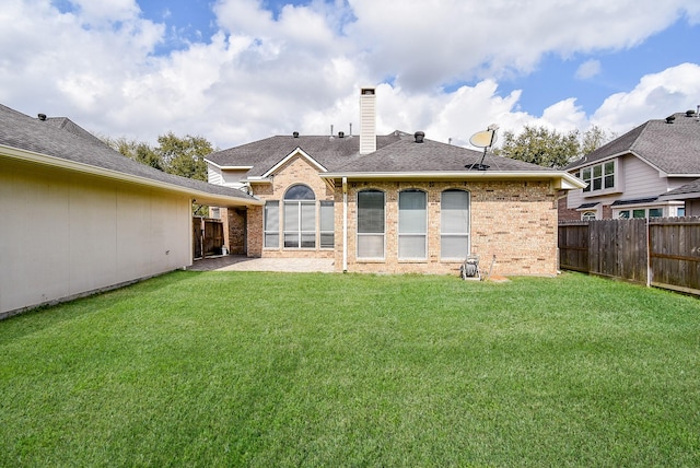 rear view of property featuring a yard, brick siding, a chimney, and fence