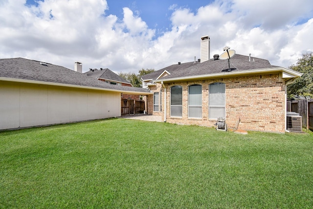 back of house with brick siding, a yard, and a chimney