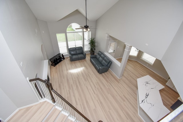 living room with high vaulted ceiling, wood finished floors, and baseboards