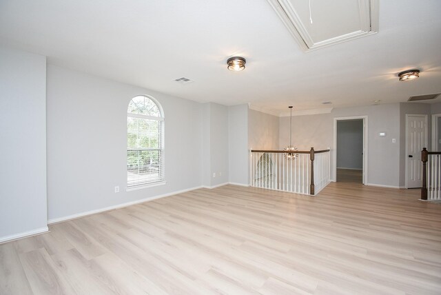 empty room with attic access, visible vents, and light wood-style floors