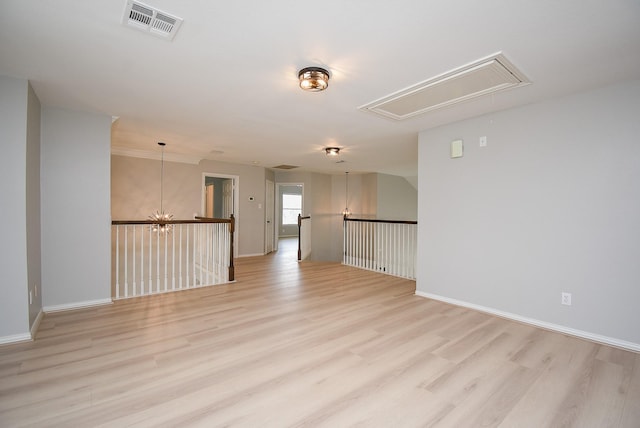 unfurnished room featuring visible vents, light wood finished floors, attic access, and baseboards