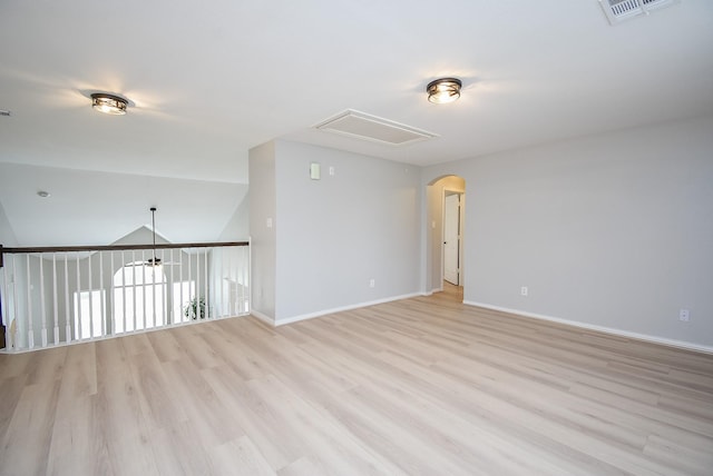 spare room with lofted ceiling, baseboards, visible vents, and light wood finished floors