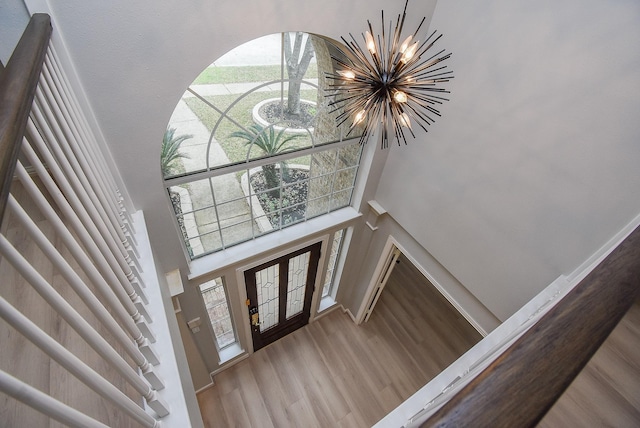 foyer entrance with a notable chandelier, a towering ceiling, wood finished floors, baseboards, and stairs