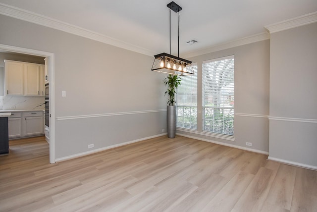 unfurnished dining area with crown molding, baseboards, visible vents, and light wood-style floors