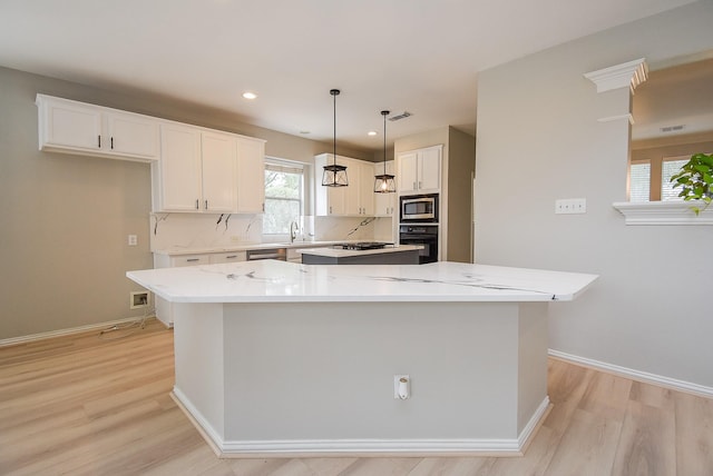 kitchen featuring visible vents, white cabinets, a kitchen island, appliances with stainless steel finishes, and a sink