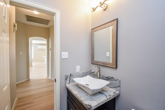 bathroom with visible vents, vanity, baseboards, and wood finished floors