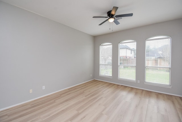 spare room featuring light wood-style flooring, baseboards, and ceiling fan