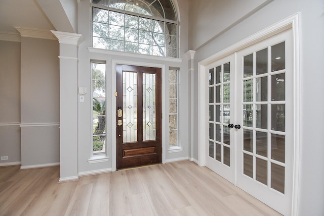 entrance foyer with a healthy amount of sunlight, ornate columns, and wood finished floors