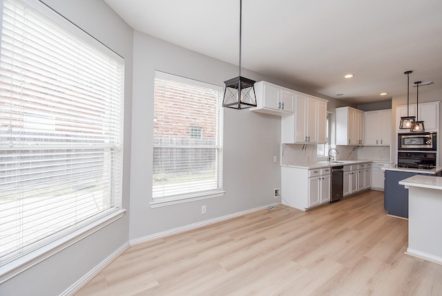 kitchen with tasteful backsplash, light countertops, stainless steel microwave, a healthy amount of sunlight, and white cabinetry