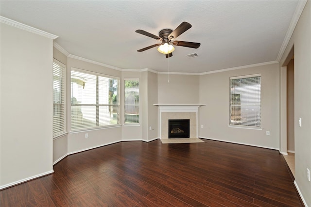 unfurnished living room with visible vents, a tiled fireplace, ceiling fan, ornamental molding, and wood finished floors