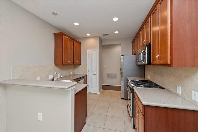 kitchen with appliances with stainless steel finishes, a peninsula, light tile patterned flooring, light countertops, and recessed lighting